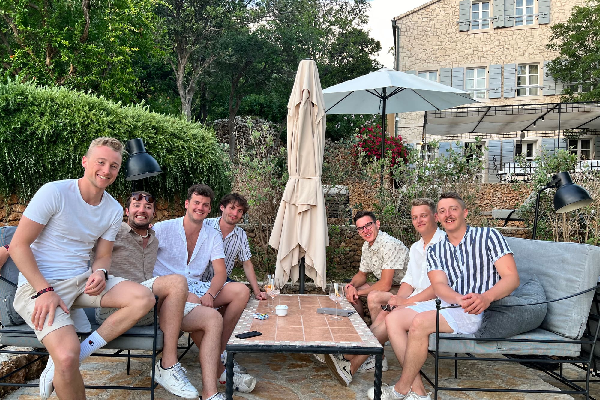 Seven of the team sitting together around a low table on a terrace on a summer evening